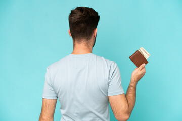 Sticker - Young caucasian man holding a wallet isolated on blue background in back position