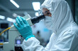© He - scientist in white hazmat suit examining sample microscope