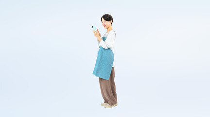 Poster - 笑顔でスマホを使うエプロンをつけたミドル女性の全身写真