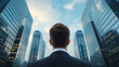 © Keopaserth - man in suit stands in front of tall skyscrapers, gazing upward at modern architecture. scene conveys ambition and determination in urban environment