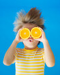© Sunny studio - Funny kid with his hair standing on end. Surprised child holding slices of orange