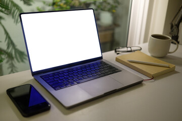 Fototapete - Cozy workspace with laptop displaying a blank screen, notebook, coffee cup and glasses, for portraying productivity and creativity during quiet hours.