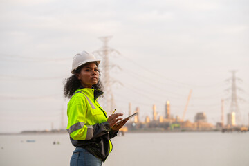 Wall Mural - Engineers wearing safety gear, including hard hats examining survey standing industrial facility gas or oil refinery engaged in a job requires high safety standards concept.	