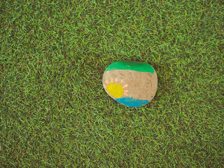 Colorful painted rock resting on green grass in a bright outdoor setting