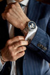 © Sergey - White man checking cufflinks with wristwatch close up