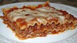 © Sanichiro - A portion of lasagna, showing layers of pasta, meat sauce, and melted cheese.