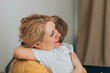 © Айман Дайрабаева - mother embracing her son with warmth in a cozy home environment concept of family support, mental health, child psychology