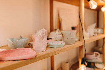 Poster - Shelf with handmade clay cups and plates in the pottery studio. Creating ceramics ware with own hands.