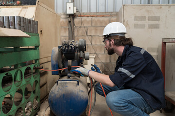 Poster - Professional male engineer worker working with air compressor in the industry factory. Male engineer worker checking or maintenance air compressor machine