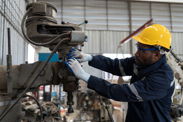 Fototapete - Professional male engineer maintenance lathe machine in industry factory. African American male engineer repairing lathe machine with safety uniform, goggles and helmet