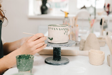 Fototapete - Artist is decorating and painting handmade ceramic clay cup in the creative workshop. Painter is drawing and adding unique designs to the earthenware.