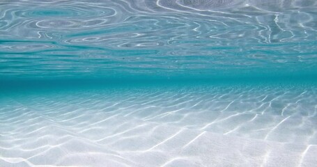 Wall Mural - Transparent clear blue ocean with sandy sea bottom underwater, sea background with waves in sunny day