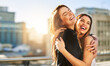 © Donson2000/peopleimages.com - Happy women, city and hug with love for travel, friendship or celebration together in an urban town. Female people, friends and joy with laughter on balcony for support, trust or holiday weekend