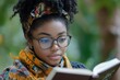 © Michael - Young black woman wearing glasses and a headscarf is immersed in a book, enjoying a quiet moment outdoors