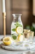 © Kassiopeia  - A carafe filled with lemon and mint infused water is elegantly displayed on a small marble tray. Beside it, gold-accented glasses catch the light in a softly blurred wooden backdrop