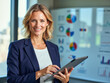 © f_bossa - headshot portrait photo of a business person: A woman standing in front of a whiteboard holding a tablet.