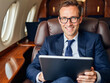 © f_bossa - headshot portrait photo of a business person: A man in a suit sitting in an airplane using a tablet.