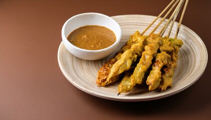 Indonesian satay food on a plate with peanut sauce, isolated brown background, copy space