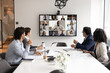 © fizkes - Multiethnic different aged business team speaking to distant colleagues on group conference chat. African American company leader man talking to staff from large display on online and offline meeting