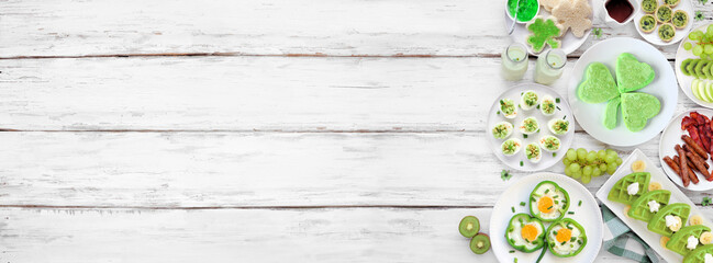 Poster - St Patricks Day breakfast or brunch side border against a white wood banner background. Selection of green and shamrock themed pancakes, toasts, eggs, fruits and meats. Top down view. Copy space.
