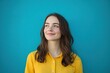 © Tuyres - Smiling Young Beautiful Woman in a Bright Yellow Shirt Against a Blue Background. Generative AI.