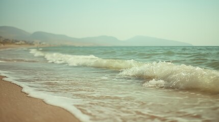 soft waves on sandy beach teal ocean and hazy mountains summer seascape