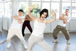 © JackF - Happy enthusiastic young girl honing hip-hop moves in modern dance studio setting with group of women and men