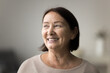 © fizkes - Smiling pretty mature female looks into distance with gentle smile, close up head shot portrait of optimistic older woman casually dressed stare aside with dreamy expression. Future, nostalgia, recall