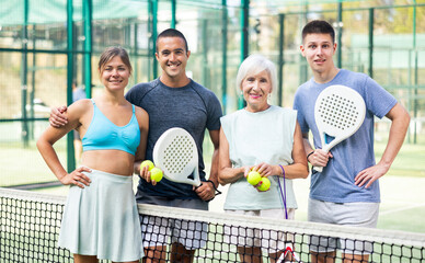 Wall Mural - Portrait of four happy padel players on the tennis court outdoor