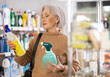 © JackF - Uncertain mature female buyer choosing convenient spray surface cleaner in department store