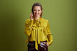 © Alliance - smiling trendy woman talking on smartphone on green background