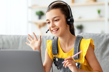 Poster - E-learning Concept. Portrait of cheerful teenage pupil sitting at table, using laptop having virtual conference, waving hand to webcam greeting teacher and classmates, talking and answering question