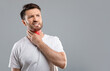 © Prostock-studio - Middle aged sick man having sore throat, looking at copy space over grey studio background. Bearded man touching his red neck, suffering from throat disorder, tonsillitis, throat cancer, cold