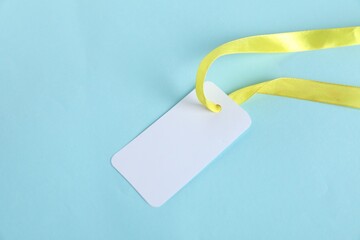 Wall Mural - Blank tag with ribbon on light blue background, top view