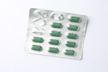 Wall Mural - Blister with green pills on white background, top view