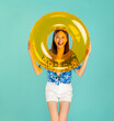 © sitthiphong - Songkran festival in Thailand, Full body length happy smiling young Asian woman in summer wearing floral shirt with plastic glasses and holding yellow inflatable ring in blue background.
