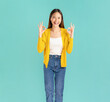 © sitthiphong - Happy smiling young Asian woman casual yellow shirt and standing with shows ok sign, isolated on blue background.