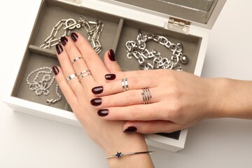 Wall Mural - Woman wearing beautiful rings and jewelry box with different accessories on white background, closeup