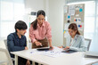 © Leny Studio - A business meeting where a woman leads a discussion with two colleagues, analyzing documents and collaborating at a modern workspace.