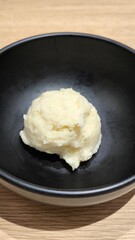 Wall Mural - Mashed potatoes in a black cup on a wooden table