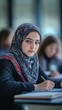 © Sawitree88 - A Muslim student taking notes in class. student wearing a headscarf and writing intently.