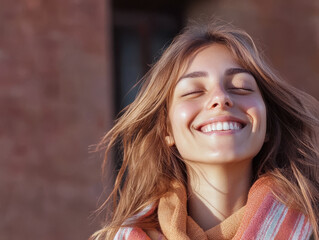 Joyful young woman smiling in warm sunlight with soft wind blowing in her hair