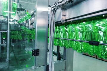 Poster - bottled beverage production process in a factory with green plastic bottles on a conveyor belt