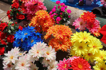 A Collection of artificial plastic Flowers in pots in vibrant colors, shapes, sizes at a street vendor shop in India.