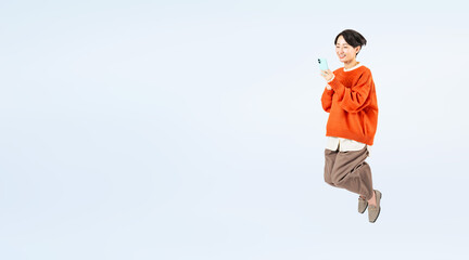 Aufkleber - スマホを見ながらジャンプするおしゃれなミドル女性の全身写真（切り抜き背景透過PNGも販売しております。作成者リンクから「PNG」で検索してください）