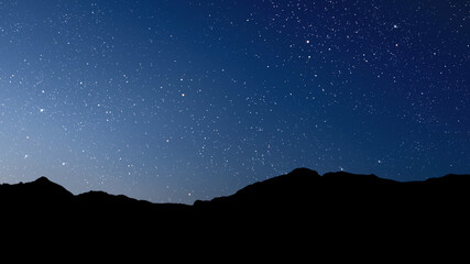 Wall Mural - a movement of stars in the night sky with the view of mountains..