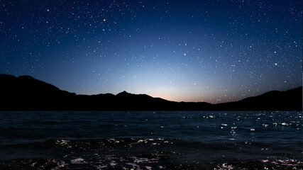 Wall Mural - a movement of stars in the night sky with the view of mountains..