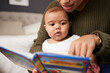 © Malambo20/peopleimages.com - Bed, mother and reading book to baby for brain development, language skills and bonding together. Woman, infant and storytelling in home for learning support, education and imagination in bedroom