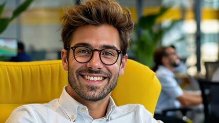 Poster - Man wearing glasses and a white shirt is smiling in a yellow chair. Concept of happiness and relaxation