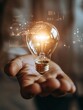 © RaptorWoman - A hand holds a glowing light bulb, symbolizing innovation and technology, surrounded by digital data and futuristic graphics.